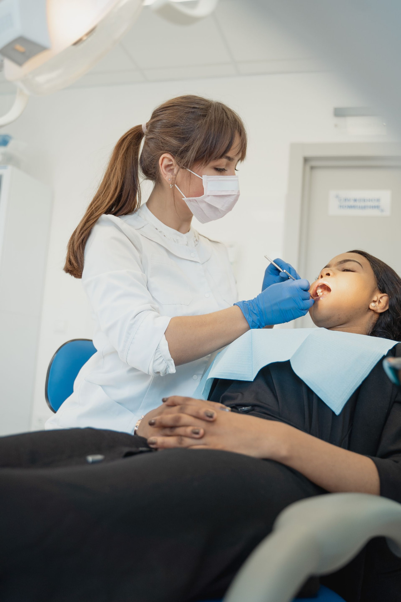 Dentist in blue gloves treating a patient seated in a dental chair